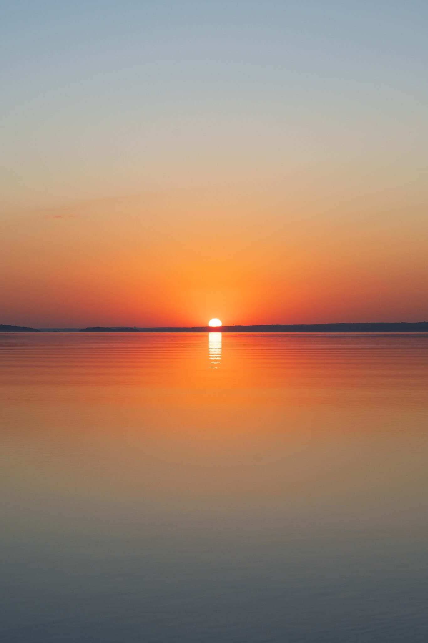 Sunrise over calm water with a glowing orange reflection photographed by Nick DiBari
