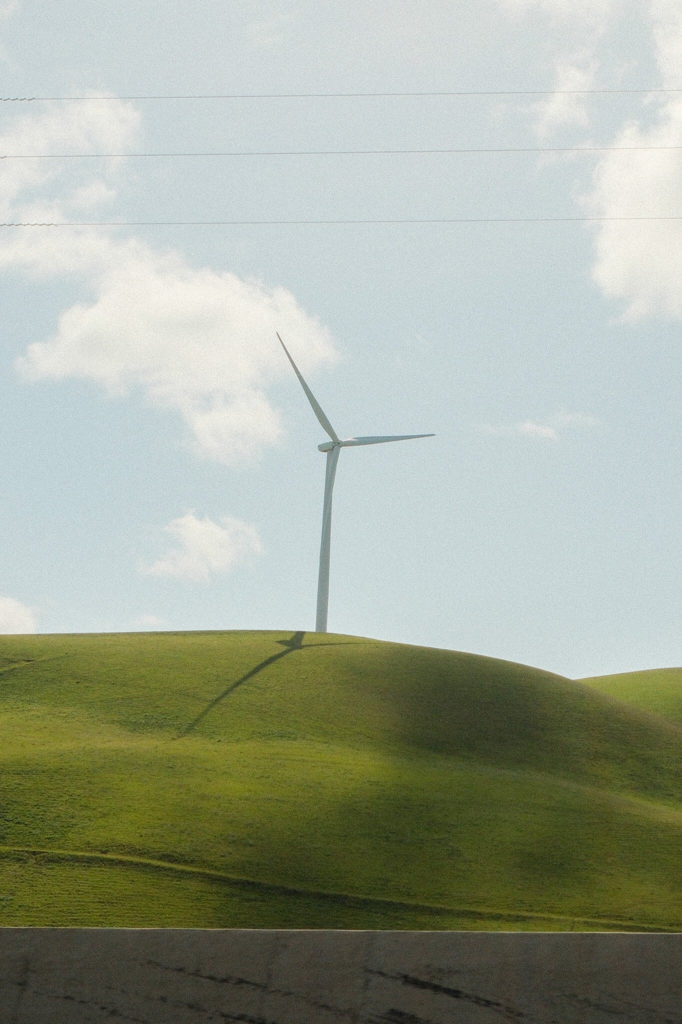 Wind turbine on rolling green hills photographed by Nick DiBari